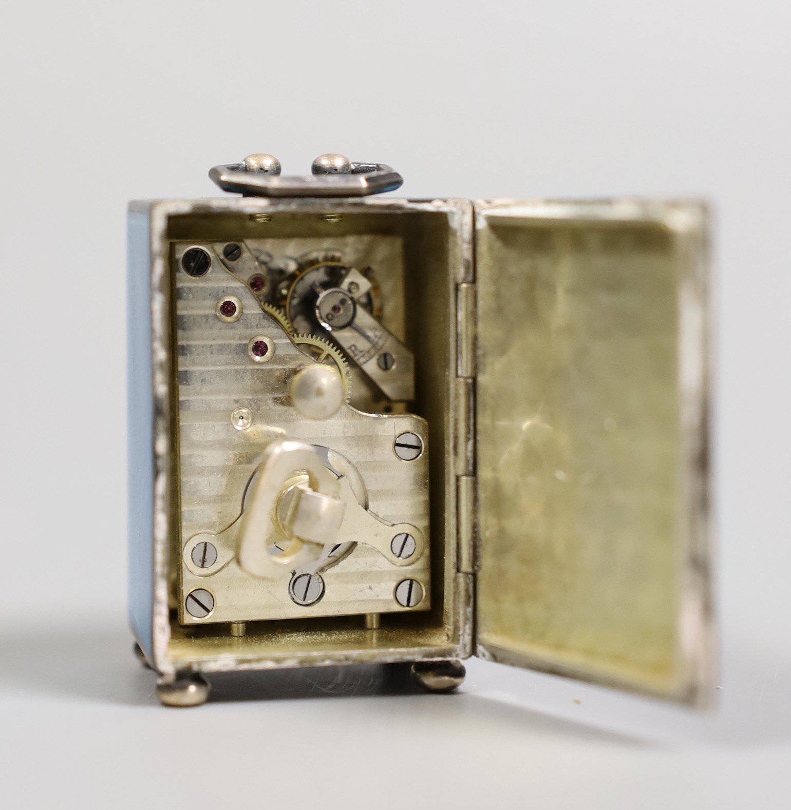A George V Swiss blue enamel and silver cased miniature carriage timepiece, import marks for Arthur George Rendell, London, 1924, 43mm, on bun feet, in gilt tooled leather carrying case